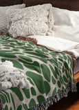 Zuma Animal Print Cotton Blend Blanket Throw in Green, draped over a chair