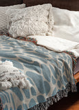 Zuma Animal Print Cotton Blend Blanket Throw in Light Blue, draped over a chair