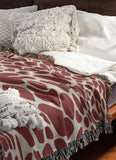 Zuma Animal Print Cotton Blend Blanket Throw in Red, draped over a chair